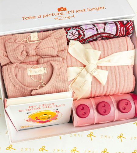 Adorable baby gift box featuring pink clothing, a puzzle book, and storage containers.